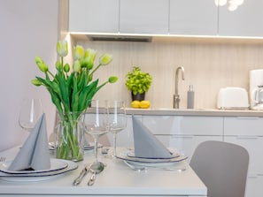 Ein Esstisch gedeckt mit Tellern, Gläsern und einer Vase mit grünen Tulpen.