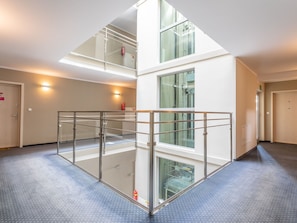 Ein mehrgeschossiges Interieur mit Glasgeländern, einem Feuerlöscher und einem Rauchmelder im Obergeschoss.