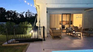 Eine Außenpatio-Terrasse mit Pool, einer überdachten Sitzgelegenheit und Blick auf den Garten.