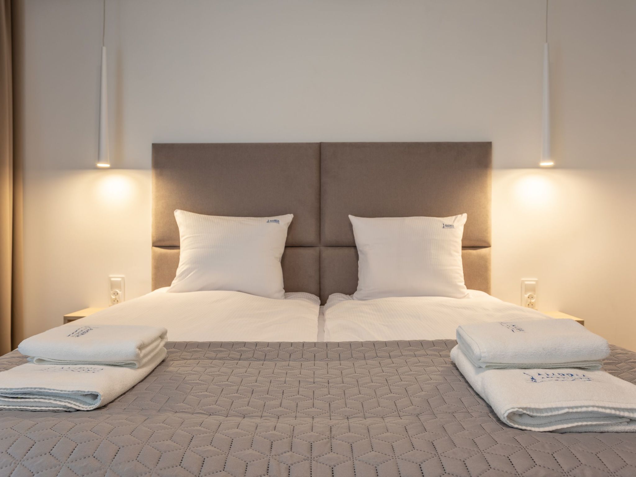 Un letto matrimoniale con testiera, due cuscini e due comodini con lampade.