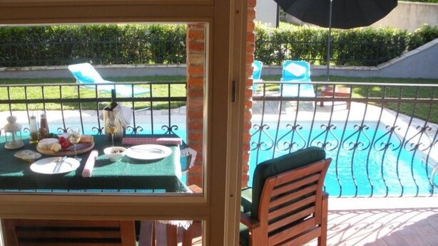 Un patio con mesa lista para comer, una piscina y mobiliario exterior.