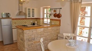 Una cocina compacta con una isla central, una mesa de comedor y un refrigerador.