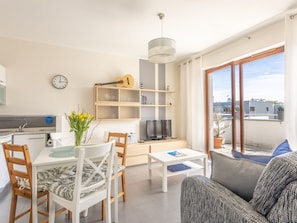 A modern living room with a dining area, a TV, and a balcony with a view of buildings. - Sky mit Balkon am Meer by Interhome (Swinoujscie)