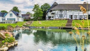 Uma casa tradicional em estilo de enxaimel, com um lago e um gramado bem cuidado.