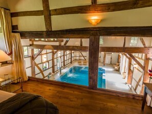Una habitación con un gran ventanal con vistas a una piscina, vigas de madera y una zona de estar acogedora.