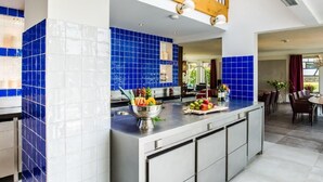 A modern kitchen with blue and white tiles, a central island with fruit, and a dining area with a view. - Geräumiges Ferienhaus in Mechelen mit by Interhome (Mechelen)