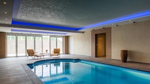 A swimming pool with a tiled floor, a few lounge chairs, and a door in the background. - Geräumiges Ferienhaus in Mechelen mit by Interhome (Mechelen)
