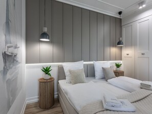 A modern bedroom with a large bed, bedside tables with plants, and a wall with vertical paneling. - Jachtowa mit Terrasse auf Usedom by Interhome (Swinoujscie)