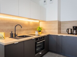 A modern kitchen with a black sink, stainless steel appliances, and a wooden backsplash. - Ferienappartement im Sun Tower an der Ostsee by Interhome (Swinoujscie)