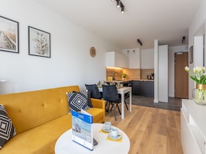 A modern living room with a yellow sofa, a dining area with a white table, and a kitchen in the background. - Ferienappartement im Sun Tower an der Ostsee by Interhome (Swinoujscie)
