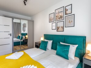 A hotel room with a large bed, a mirror, a wardrobe, and a wall with framed pictures. - Ferienappartement im Sun Tower an der Ostsee by Interhome (Swinoujscie)