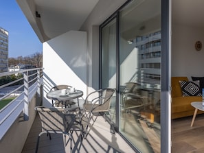 A balcony with a glass door, wicker chairs, a small table, and a yellow sofa. - Ferienappartement im Sun Tower an der Ostsee by Interhome (Swinoujscie)