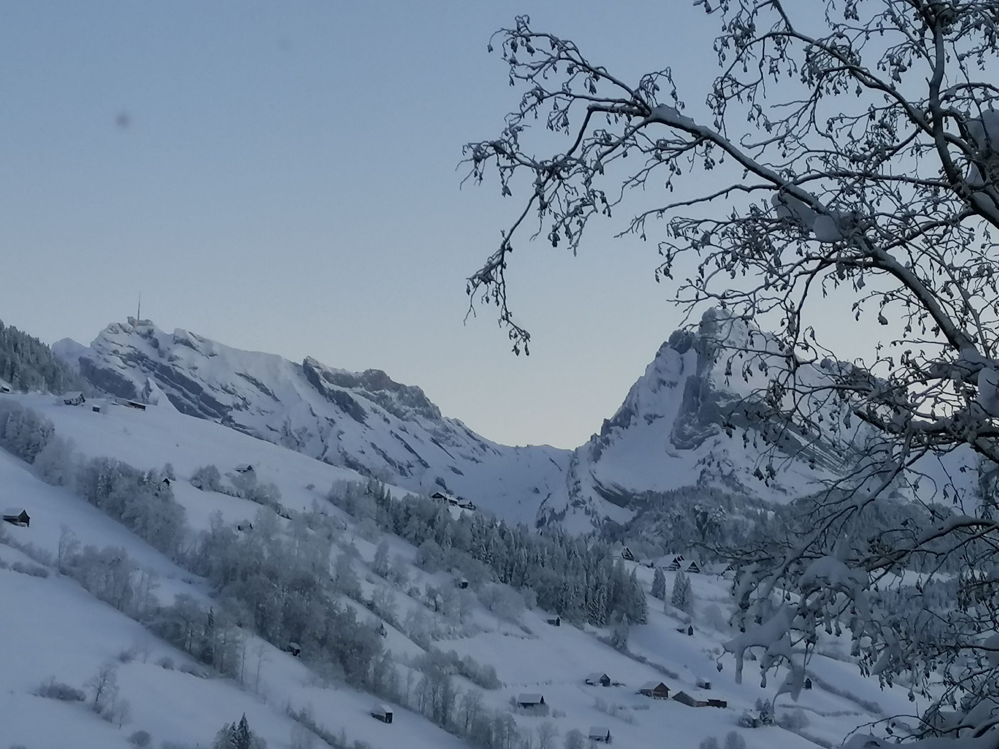 Lumipeitteinen vuoristomaisema kirkkaalla taivaalla.