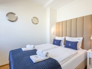 Ein Hotelzimmer mit zwei Betten, einem Kopfteil, an den Wänden befestigten Spiegeln und ordentlich gefalteten Handtüchern.