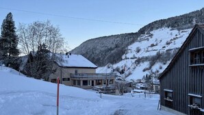 A snow-covered village with buildings, a wooden structure, and a mountain in the background.