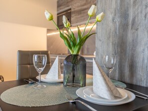 A dining table with a vase of white tulips, two folded napkins, and a glass of water. - Ferienappartement Aurora auf der Insel Usedom by Interhome (Swinoujscie)