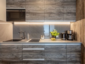 Cozinha moderna com micro-ondas embutido, pia de aço inoxidável e máquina de café.