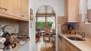 Cozinha com armários de madeira, pia e área de refeições com mesa e cadeiras.