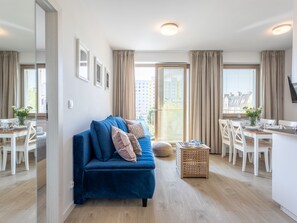 A modern apartment with a blue sofa, dining table, and chairs. - Verano direkt am Meer by Interhome (Swinoujscie)