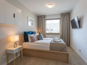 A modern hotel room with a bed, bedside table, lamp, and a TV mounted on the wall. - Verano direkt am Meer by Interhome (Swinoujscie)