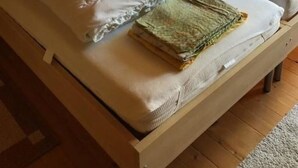 A wooden-paneled room with a large bed, a nightstand, and a lamp. - Neuer Sigerst by Interhome (Wildhaus)