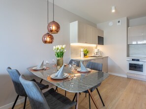 A modern dining area with a glass table, metal chairs, and copper pendant lights. - Modernes Ferienappartement in Swinemünde by Interhome (Swinoujscie)