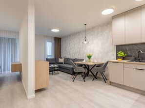 A modern living room with a sofa, a dining table with chairs, a small round table, and a kitchen area with cabinets and a sink. - Matejki in Swinemünde am Meer by Interhome (Swinoujscie)