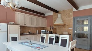 A kitchen with white cabinets, a dining table with chairs, a chandelier, and a microwave. - Wohnung mit Kamin N2 by Interhome (Zuberec)