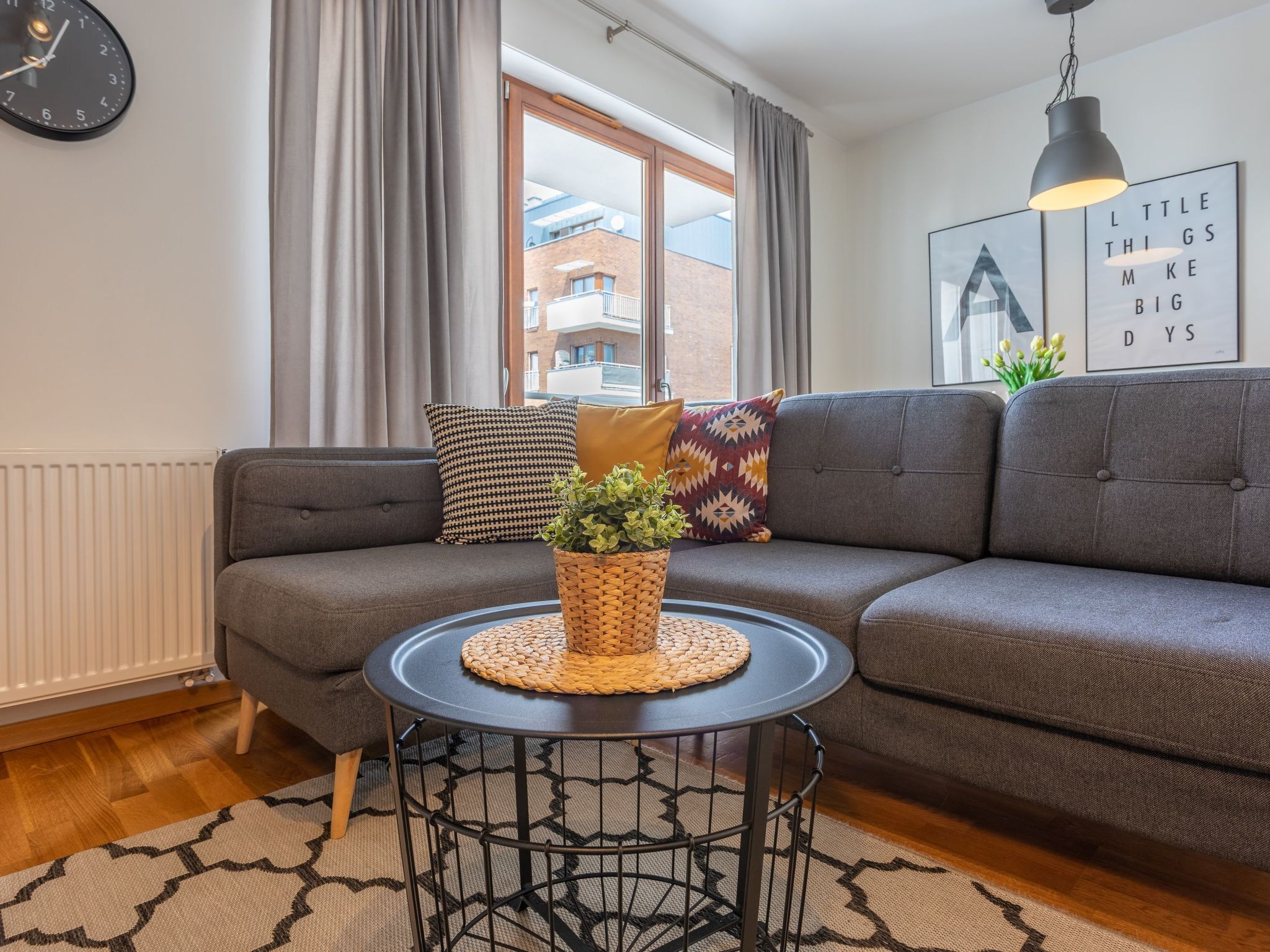 A modern living room with a grey sofa, a round coffee table, and a clock on the wall.
