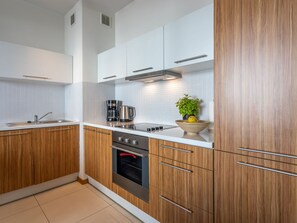 Eine moderne Küche mit Holzausstattung, einer Edelstahlspüle, einer Kaffeemaschine und einem eingebauten Backofen.