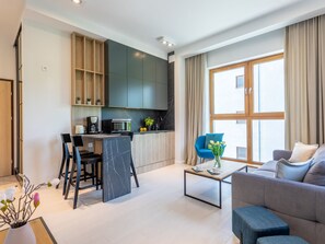 Ein modernes Wohnzimmer mit Sofa, Couchtisch und einer Essecke mit Stühlen und einer Küchenzeile.