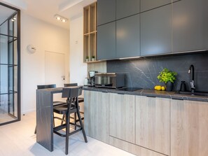 Eine moderne Küche mit dunkler Arbeitsplatte, Holzschränken und einer eingebauten Mikrowelle.