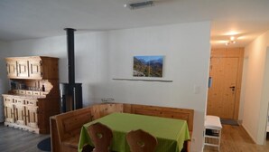 A cozy room with a wooden bench and chairs, a small table, a fireplace, and a framed picture on the wall. - Chesa Brünella, Wohnung Belvair by Interhome (Zuoz)