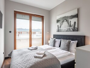 Ein Hotelzimmer mit einem großen Bett, Blick auf eine Brücke und Berge durch das Fenster sowie einem Gemälde derselben Szene an der Wand.