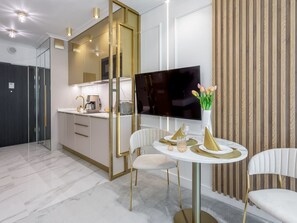 A modern kitchen with a built-in TV, white chairs, and a dining table set for four. - Sonnige Ferienwohnung am Meer by Interhome (Swinoujscie)