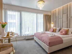 A modern hotel room with a large bed, a dining area, and a view of greenery outside. - Sonnige Ferienwohnung am Meer by Interhome (Swinoujscie)