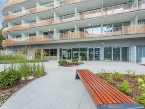 A modern multi-story building with balconies, a central courtyard, and a wooden bench. - Sonnige Ferienwohnung am Meer by Interhome (Swinoujscie)