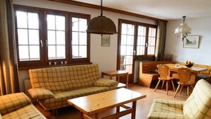 Una sala acogedora con un sofá, una mesa de centro y un comedor con muebles de madera.