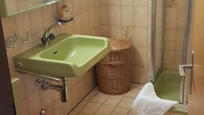 Un baño con lavamanos verde, inodoro, ducha y espejo.