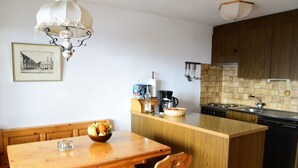 Una cocina compacta con una mesa de comedor de madera, una isla central y un horno empotrado.