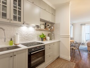 A modern kitchen with white cabinets, a built-in oven, and a stainless steel range hood. - Stilvolle Ferienwohnung Amelia in Swinemünde by Interhome (Swinoujscie)