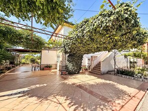 A courtyard with tiled flooring, a pergola, and potted plants. - Apartment Dragica by Interhome (Polje)