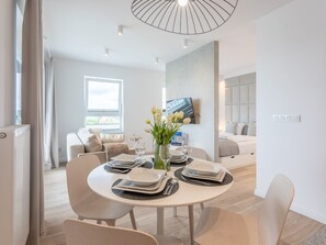 A modern dining area with a round table set for four, a sofa, and a TV mounted on the wall. - Urlaub auf Usedom, Apartment Sun Towers A53 by Interhome (Swinoujscie)