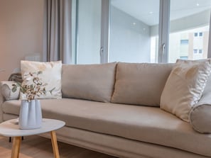 A modern living room with a beige sofa, a small round table, and a vase with flowers. - Urlaub auf Usedom, Apartment Sun Towers A53 by Interhome (Swinoujscie)
