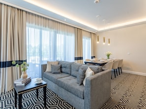 A modern living room with a grey sofa, a small coffee table, and a dining area with a table set for four. - Ferienappartement Baltic Park Fort auf Usedom by Interhome (Swinoujscie)