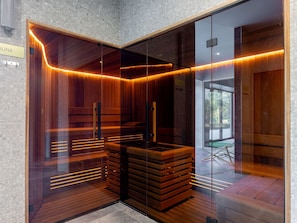 A sauna with wooden benches and glass walls, a sign indicating the sauna area, and a view of the outside through the glass. - Stilvolle Ferienwohnung am Meer by Interhome (Swinoujscie)