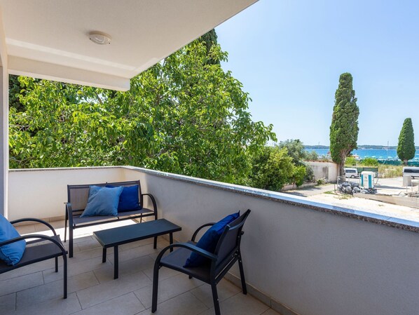 Un balcon aménagé avec du mobilier d’extérieur, une vue sur la mer et une végétation luxuriante tout autour.