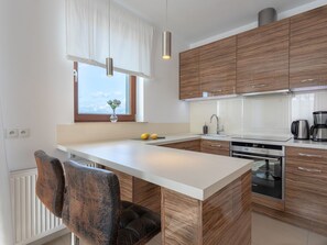 A modern kitchen with wooden cabinets, a white countertop, and a built-in dishwasher. - Glamour direkt am Meer by Interhome (Swinoujscie)