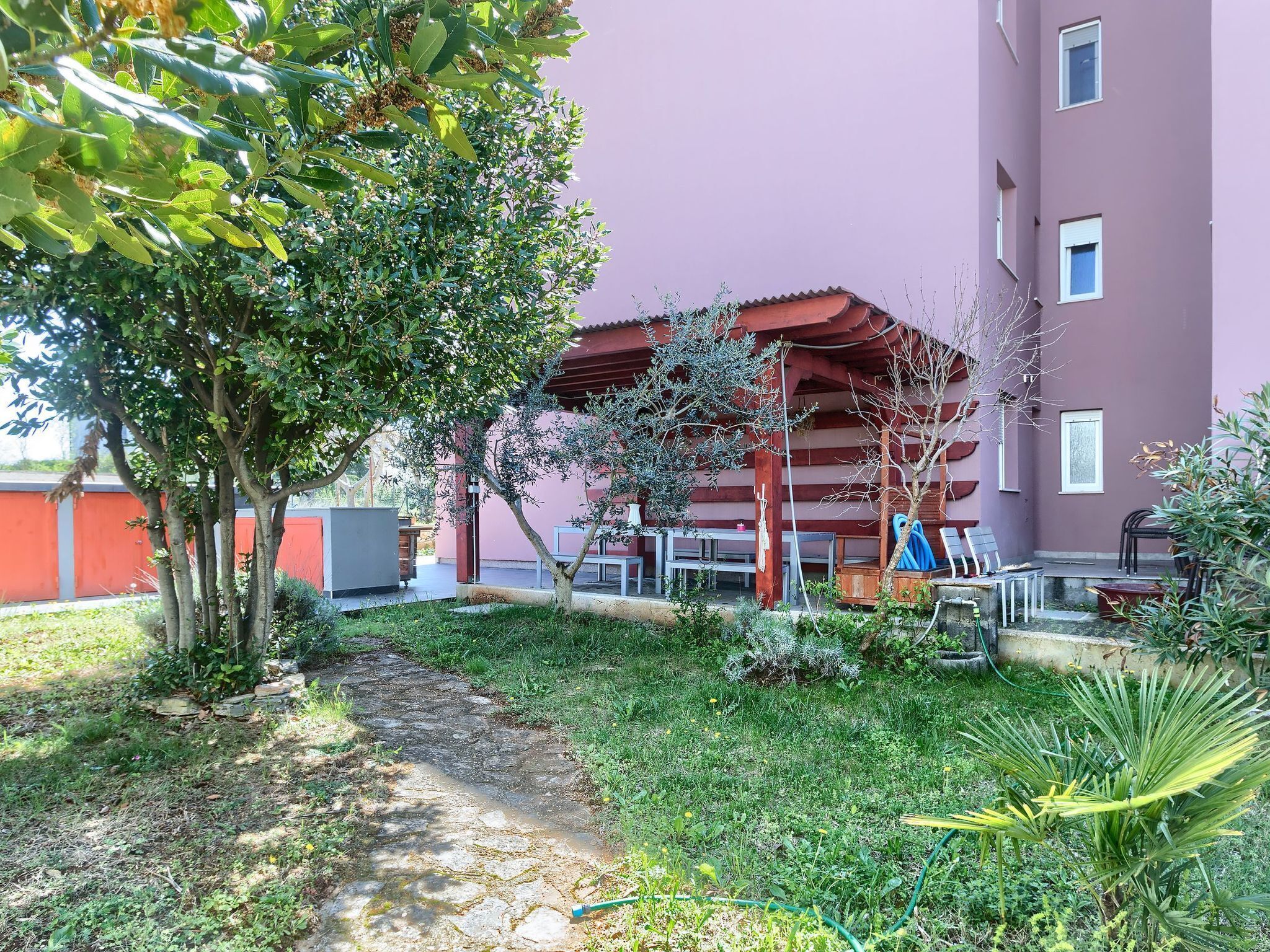 A courtyard with a covered seating area, a pathway, and a building with a red exterior.
