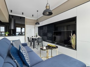 A modern living room with a blue sofa, a dining area with a table and chairs, and a kitchen with a black backsplash. - "Platan Tower 113" by Interhome (Swinoujscie)
